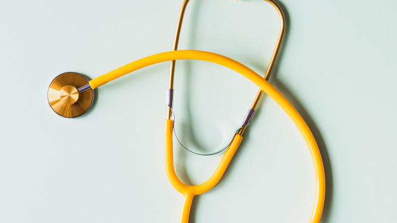 Yellow stethoscope on green background