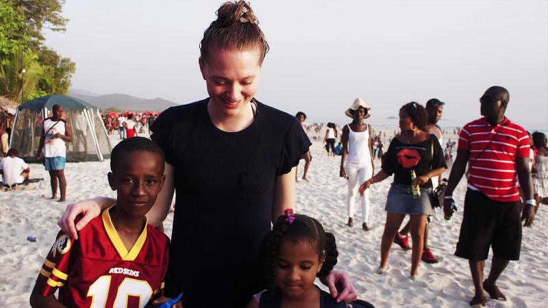 Student in Sierra Leone. Standing on a beach with locals