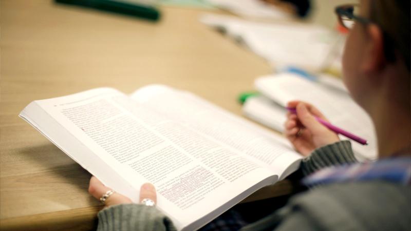 Person writing in book.