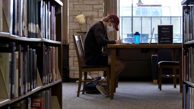 Student studying at table inside Mudd Library