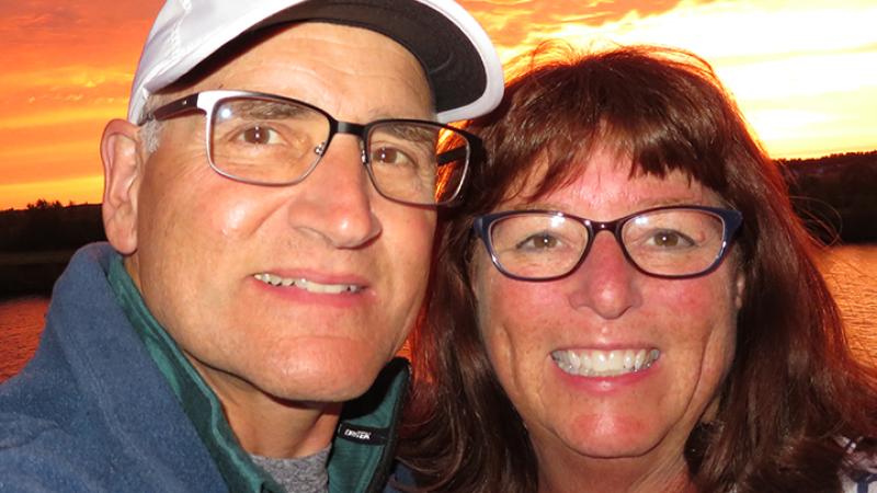 Richard Zimman ’73 & Valerie Cox pose for a picture in front of a sunset.