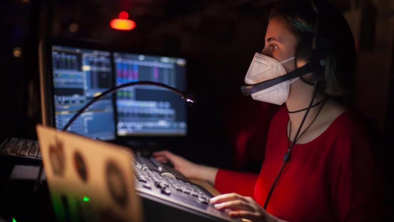 Student wearing headphones adjusts the light board