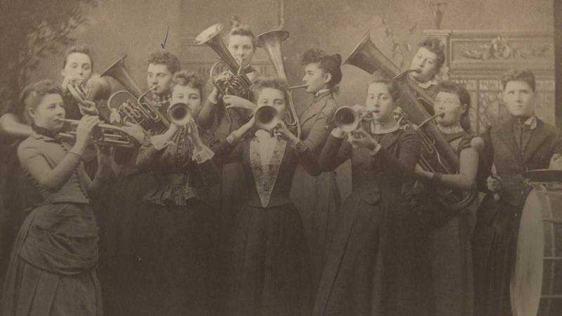 Women standing playing trumpets and other brass instruments