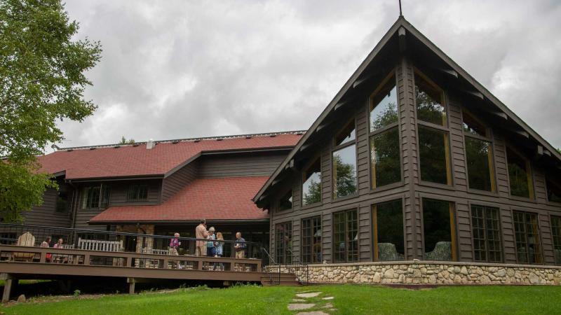 Guests relax on the deck of the main lodge during a 2019 summer seminar at Bjorklunden.