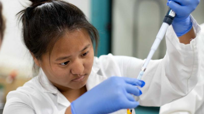 Katie Mahorney wears gloves and a lab coat as she works on research during the summer of 2021.