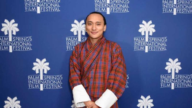 Pawo Choyning Dorji poses for a photo in front of signage for the Palm Springs International Film Festival.