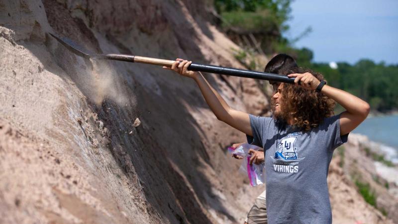 Students use shovels as they pull materials from a cliff during a research project near Two Rivers.