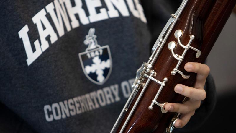 Close up of bassoon. Student wearing shirt that reads, "Lawrence Conservatory of Music"