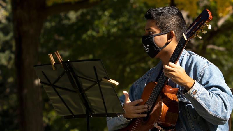 Student plays guitar outdoors