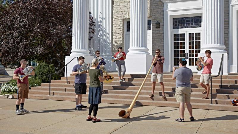 Students and faculty play horns on Memorial Chapel exterior steps.