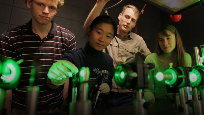 Four students gathered around laser