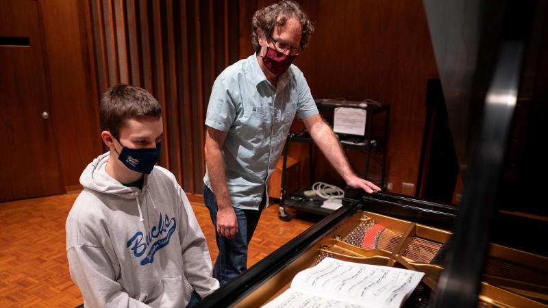 Michael Mizrahi standing by student playing piano