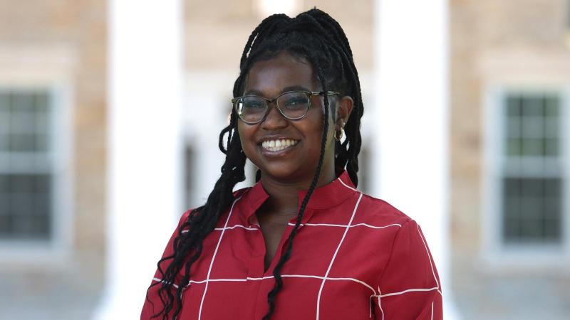 Sarah Navy smiling for a portrait, wearing a red shirt