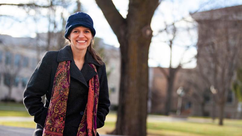 Allison Fleshman, wearing a blue hat and red scarf, smiles at the camera.