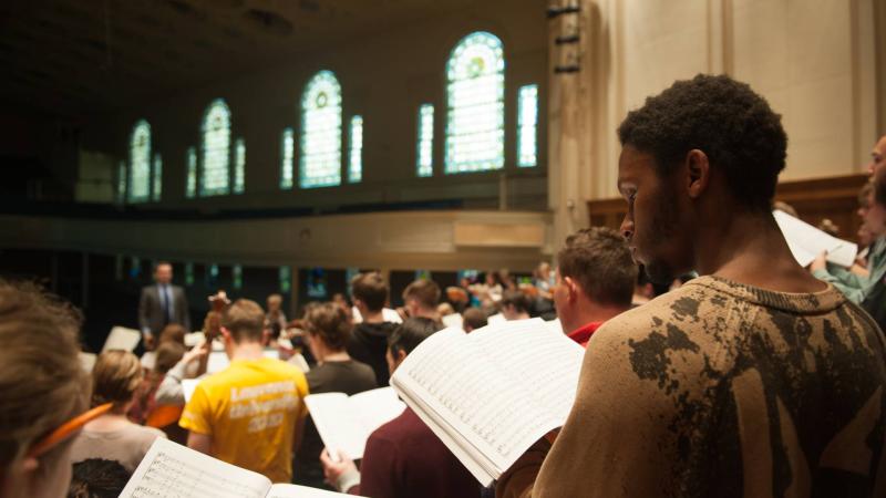 Singers with sheet music in hand during choir rehearsals in Memorial Chapel.