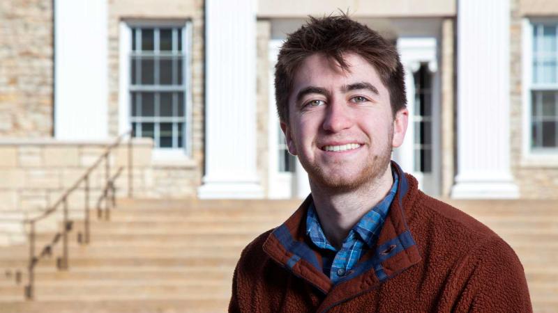 Eli Ferrell poses for a photo on the steps behind Main Hall.