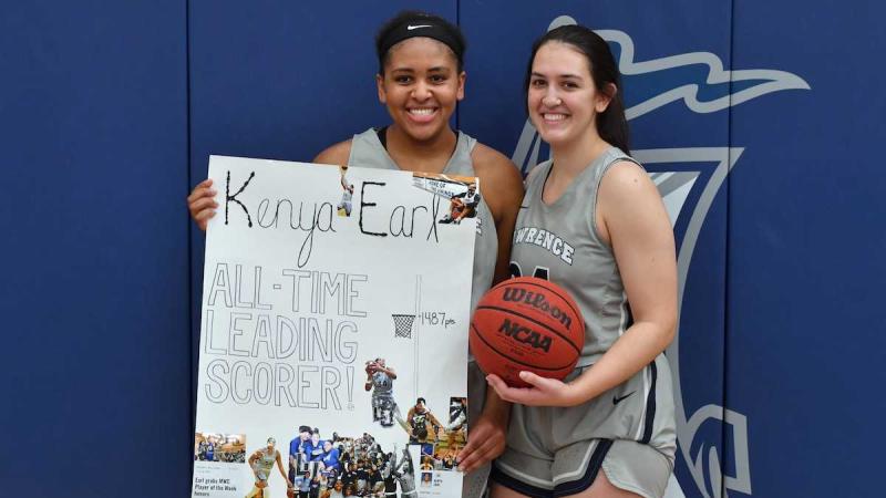 Kenya Earl stands with Karina Herrera while holding a handmade sign that says All Time Leading Scorer.