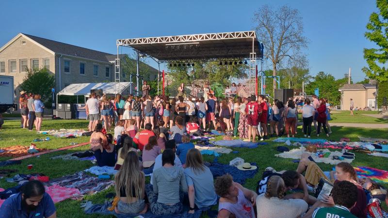 Students sitting on the lawn and crowded around the LUaroo stage in the late afternoon sun.