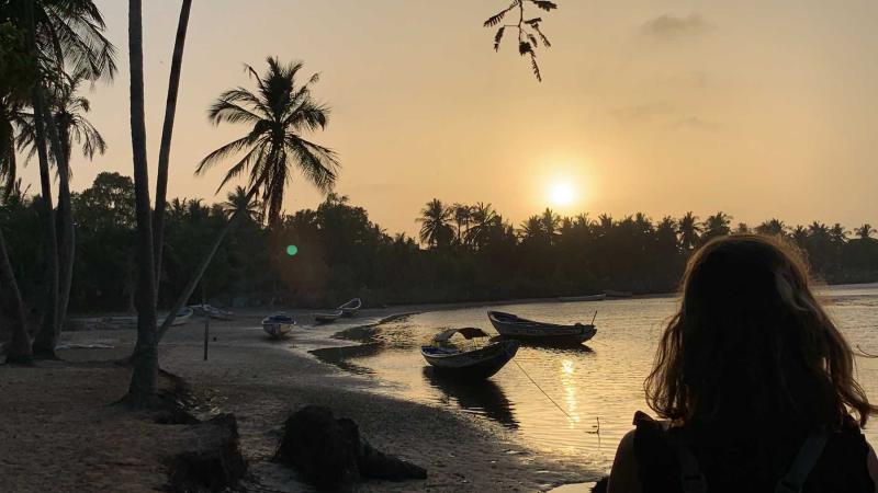 A student looks at small boats along the water's shore in Senegal.