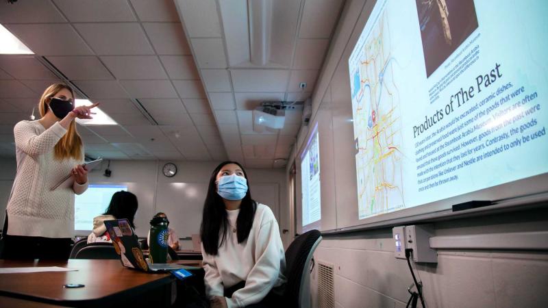 Professor Claire Kervin points at a large screen as she talks with student Juli Clarkson about her work in Environmental Justice and Citizenship.