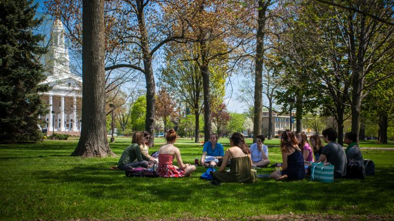 A philosophy class sits in a circle on the grass of Main Hall Green as Ingrid Albrach teaches. Memorial Chapel is in the background.