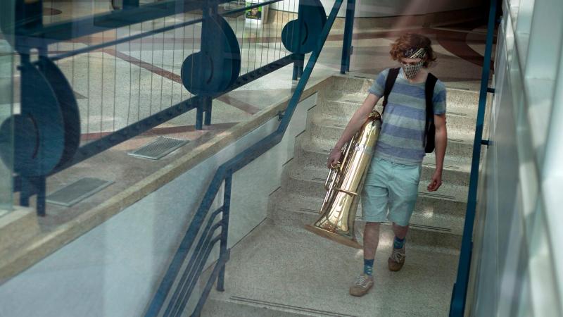 Student carries tuba down stairs in Conservatory of Music