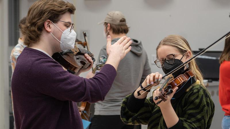 Students work together playing violins in Music Education class.