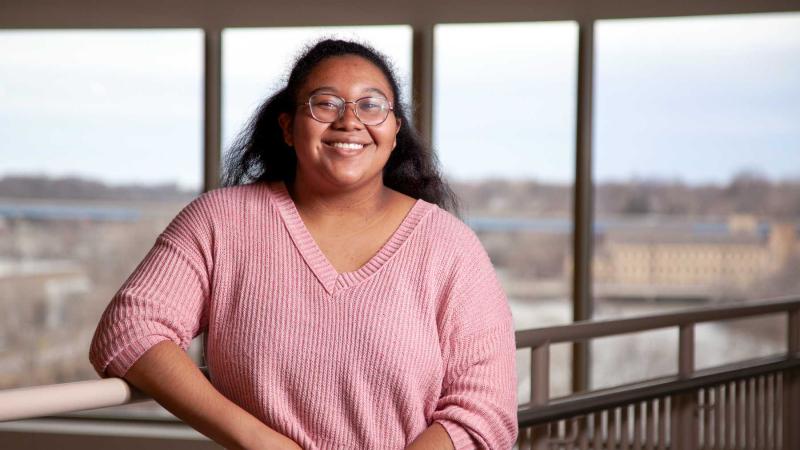 Imani Williams poses for a photo in front of large windows in the Warch Campus Center.