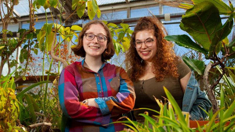 Lauren Kelly and Emma Zelles stand for a portrait in the Briggs Hall Greenhouse.