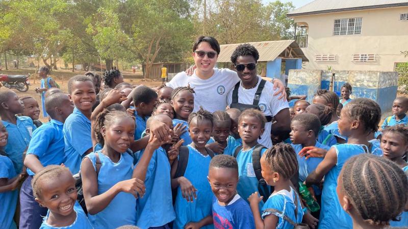 Lawrence Sid Short and Tomi Oladunjoye pose for a photo with a group of FAWE students outside the school.