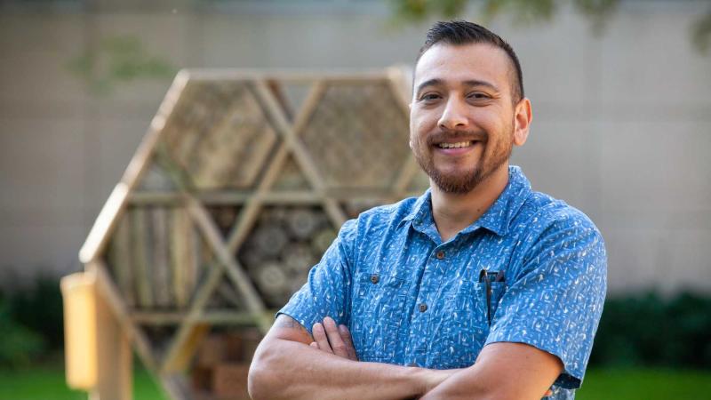 Israel Del Toro poses in front of a bee house on campus.