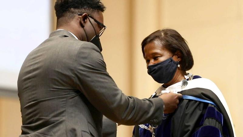 President Laurie Carter's son, Carter Walker Robinson, places the Chain of Office on his mother.