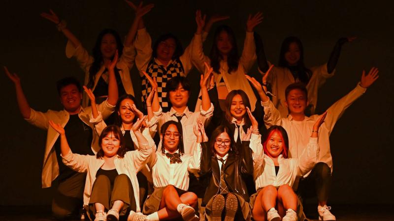 Group of students on stage with their arms raised during 2022 Cabaret performance.
