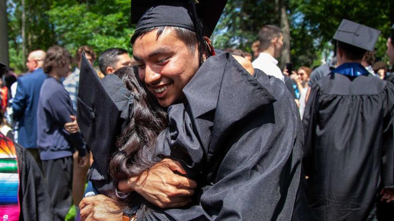 Graduates hug following the commencement ceremony.