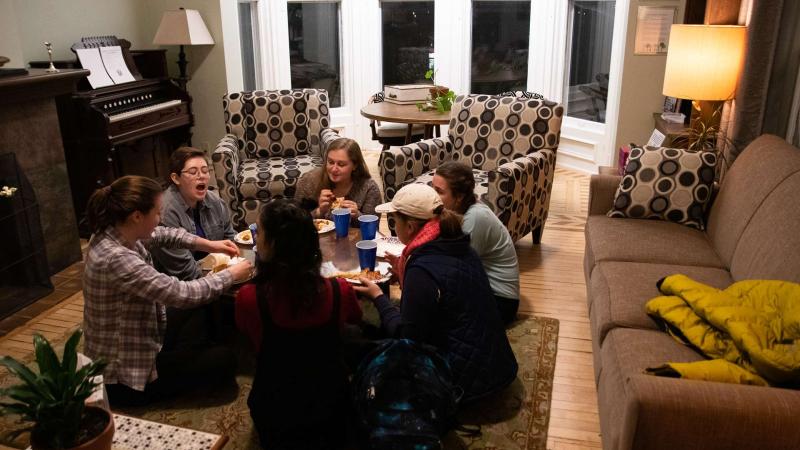 Six students sitting around coffee table eating