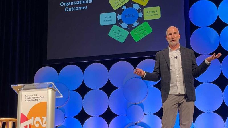 Peter Glick gestures on stage while delivering the keynote address at the American Psychological Association national convention in Minneapolis.