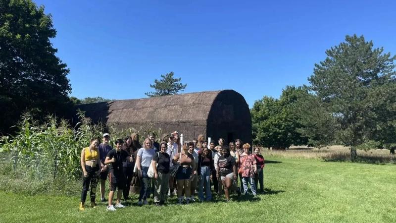 Summer Institute students taking a group picture outdoors on a sunny, clear day, at the Oneida Reservations tour.