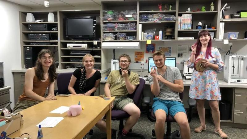 Four Summer Institute Students sitting and a Faculty Member standing in the Mudd Library Makerspace.