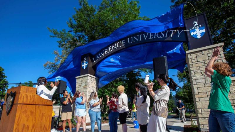 The blue tarp is pulled from the signage at the top of the Welcome Arch during the reveal on Thursday afternoon.