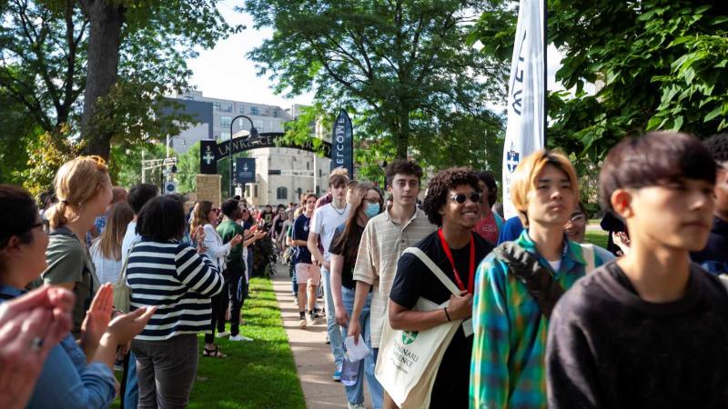 Lawrence community members line the walkway and applaud as incoming students walk through the arch.