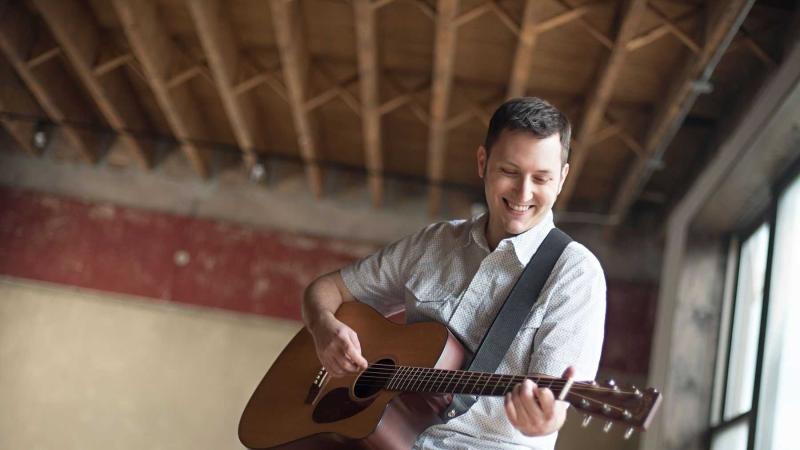 Portrait of Zachary Scot Johnson playing a guitar.