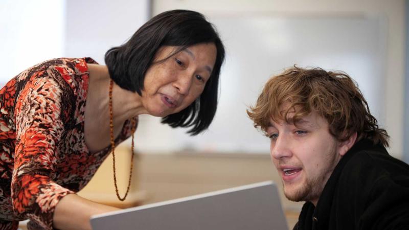 Irene Strohbeen points to the screen of a laptop as she works with junior Duval Bingham during an Innovation & Entrepreneurship class, In Pursuit of Innovation.