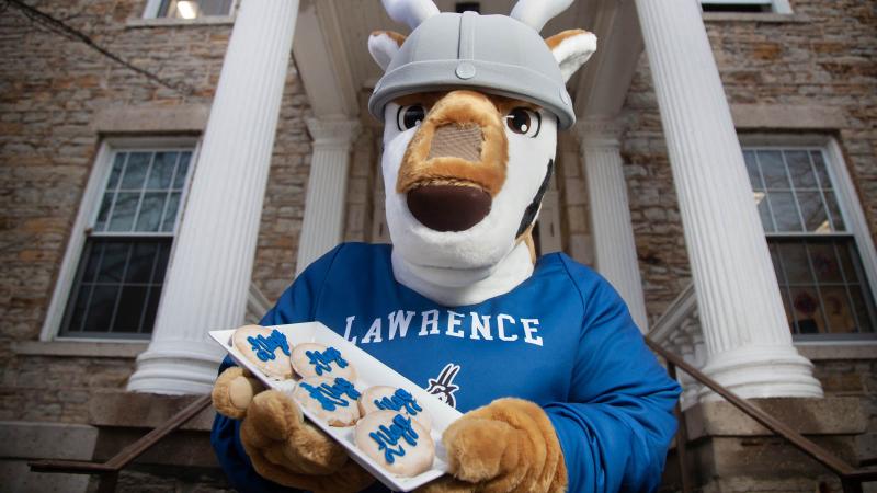 Lawrence Mascot Blu with LUgge cookies in front of Main Hall 