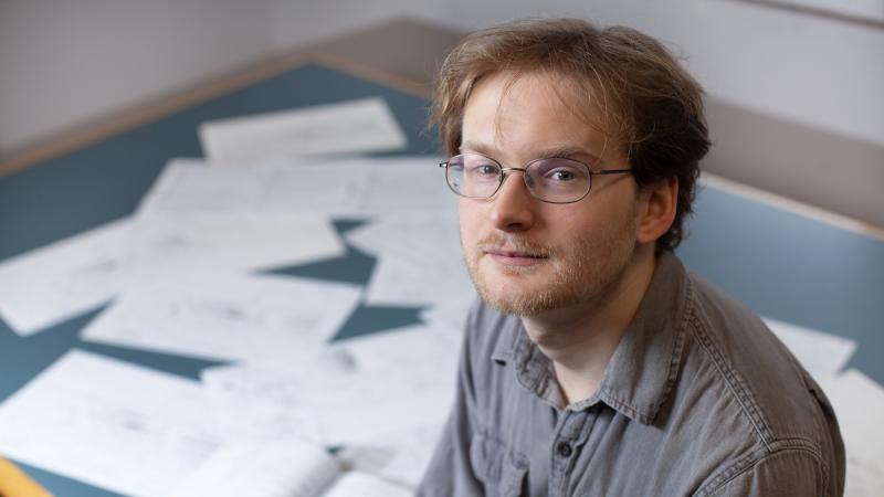 Brock Daumler poses with some of his music compositions in the background.