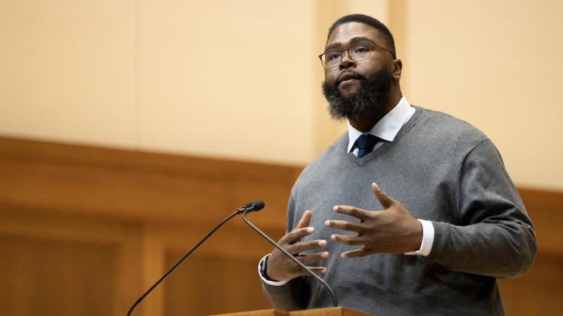 Dr. Anthony Jack gestures while speaking at the podium on the Memorial Chapel stage.