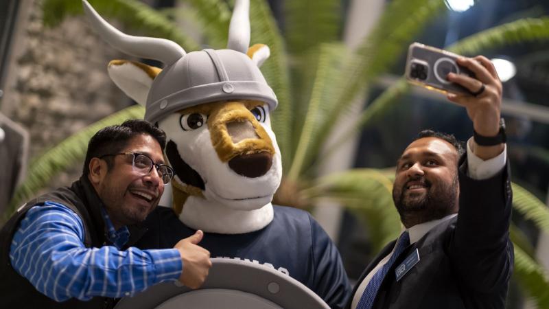 Blu mascot with alumni taking a selfie