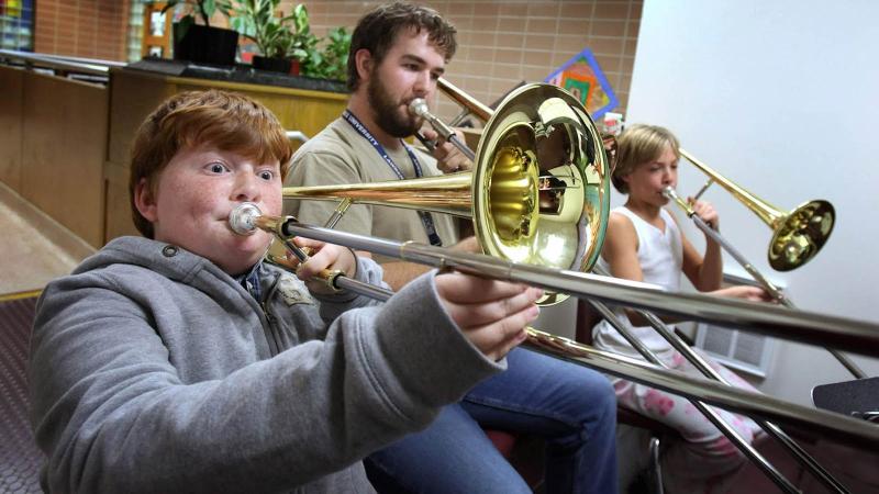 Teacher and two students practicing trombone