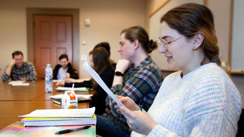 Student reading a paper to a group of students