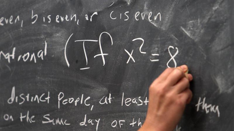 Math hero with hand writing formula on chalk board