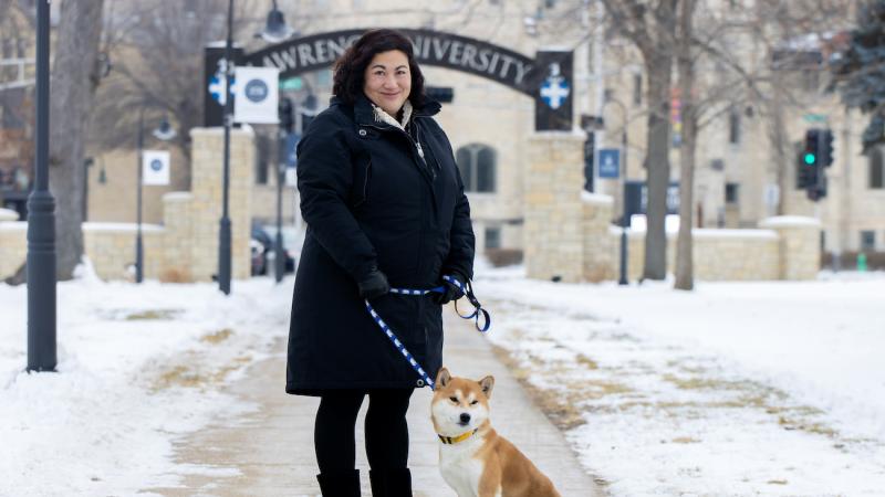 Monica Rico is joined by her dog, Connor, on the sidewalk with the Lawrence Arch in the background.